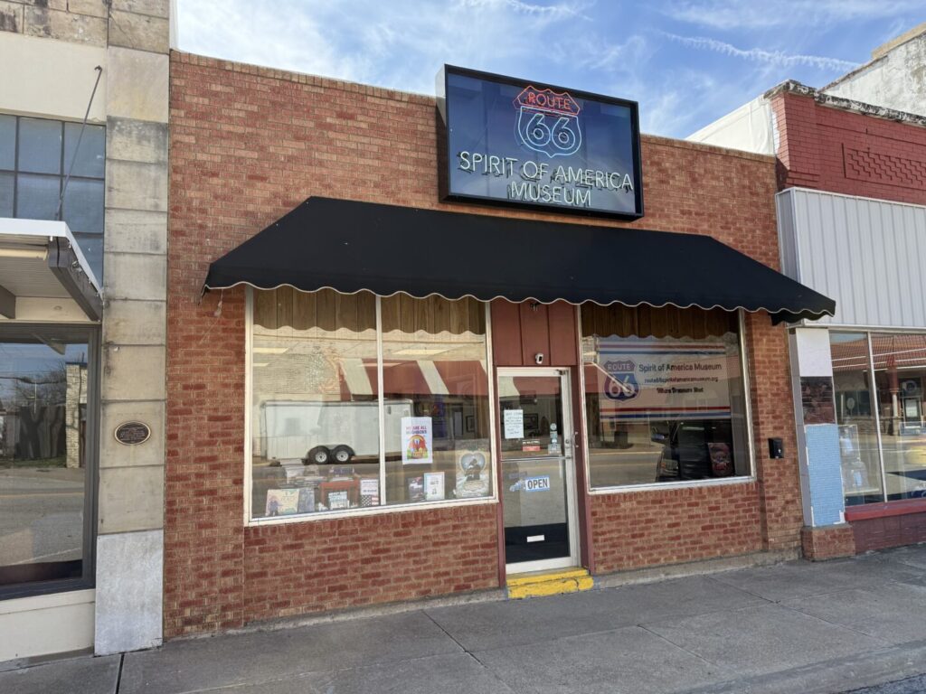 Exterior of a quaint brick storefront with a black awning and signage.